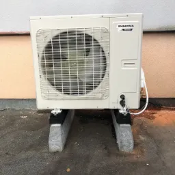 Zewnętrzna jednostka klimatyzacji Innova Inverter zamontowana na betonowych wspornikach na płaskim dachu, z widocznymi przewodami i rurami.