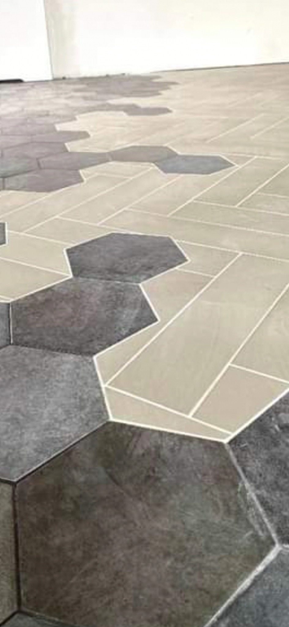 Ułożona podłoga z płytek w kształcie heksagonów i prostokątów w odcieniach szarości i beżu z białymi fugami, widok z góry.