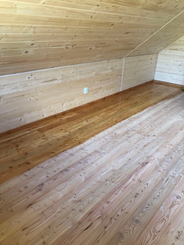 Poddasze wyłożone boazerią, z widocznym efektem lakierowania podłogi, gdzie połowa powierzchni jest już pokryta lakierem, a druga połowa w stanie surowym.