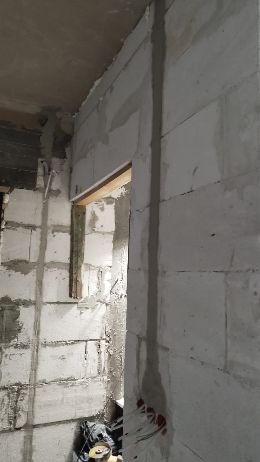 Surowy stan wnętrza z widoczną instalacją elektryczną w ścianie z betonu komórkowego, przygotowaną do dalszych prac wykończeniowych.