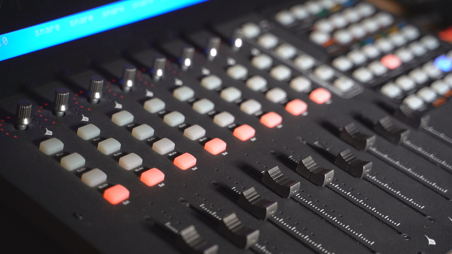 Profesjonalny mikser audio z podświetlanymi przyciskami 'Rec', 'Solo', 'Mute' i suwakami, widok z góry pod kątem.