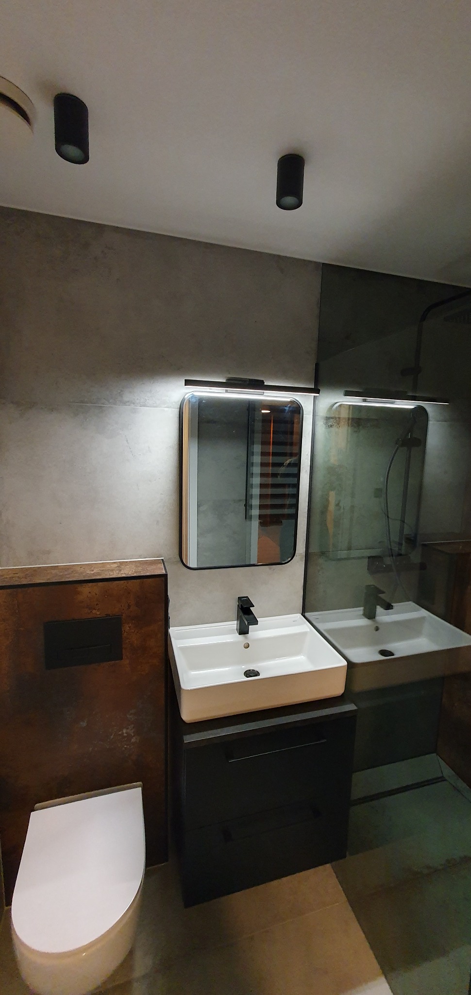 Nowoczesna łazienka z umywalką nablatową, czarną armaturą, lustrem z podświetleniem LED i toaletą w zabudowie z rustykalnym wykończeniem.