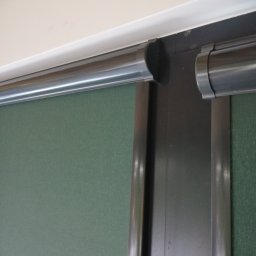 GRZEGORZ PYĆ ATOS-SERWIS ROLET - Zamknięta roleta wewnętrzna w kolorze zielonym, z widocznym mechanizmem rolety i fragmentem sufitu.