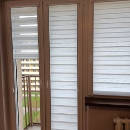 GRZEGORZ PYĆ ATOS-SERWIS ROLET - Trzy okna z białymi roletami dzień i noc, widok na balkon i budynek naprzeciwko.