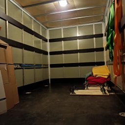 Perfekt Przeprowadzki Sylwester Troszczyński - Wnętrze przestrzeni ładunkowej samochodu dostawczego z zabezpieczeniami, pasami transportowymi i platformami na kółkach, przygotowane do załadunku mebli i sprzętów.