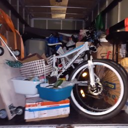 Perfekt Przeprowadzki Sylwester Troszczyński - Wnętrze furgonetki załadowane różnymi przedmiotami, w tym rowerem, pudłami, skrzynkami i narzędziami do transportu, zabezpieczonymi na czas przewozu.