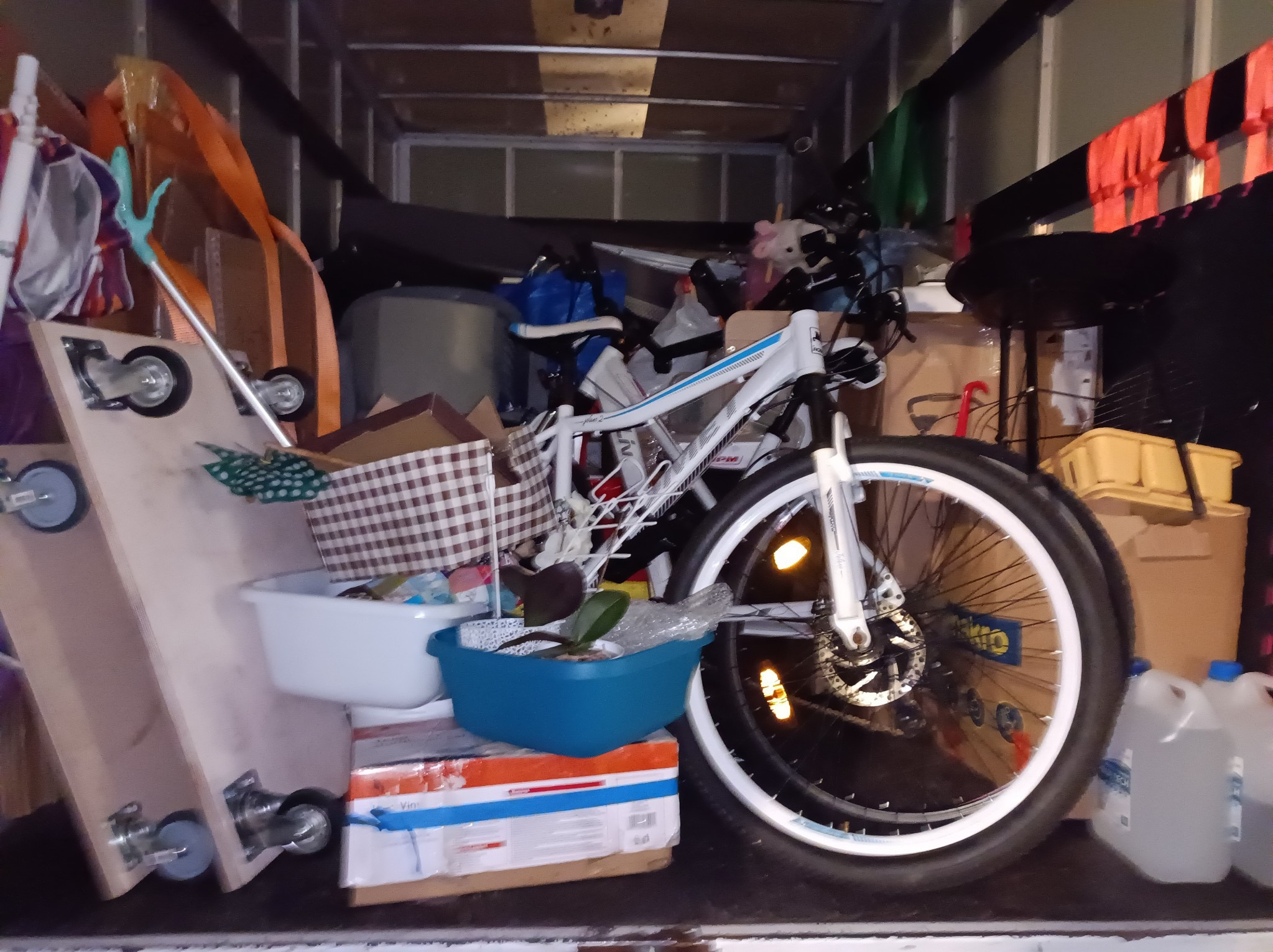 Wnętrze furgonetki załadowane różnymi przedmiotami, w tym rowerem, pudłami, skrzynkami i narzędziami do transportu, zabezpieczonymi na czas przewozu.