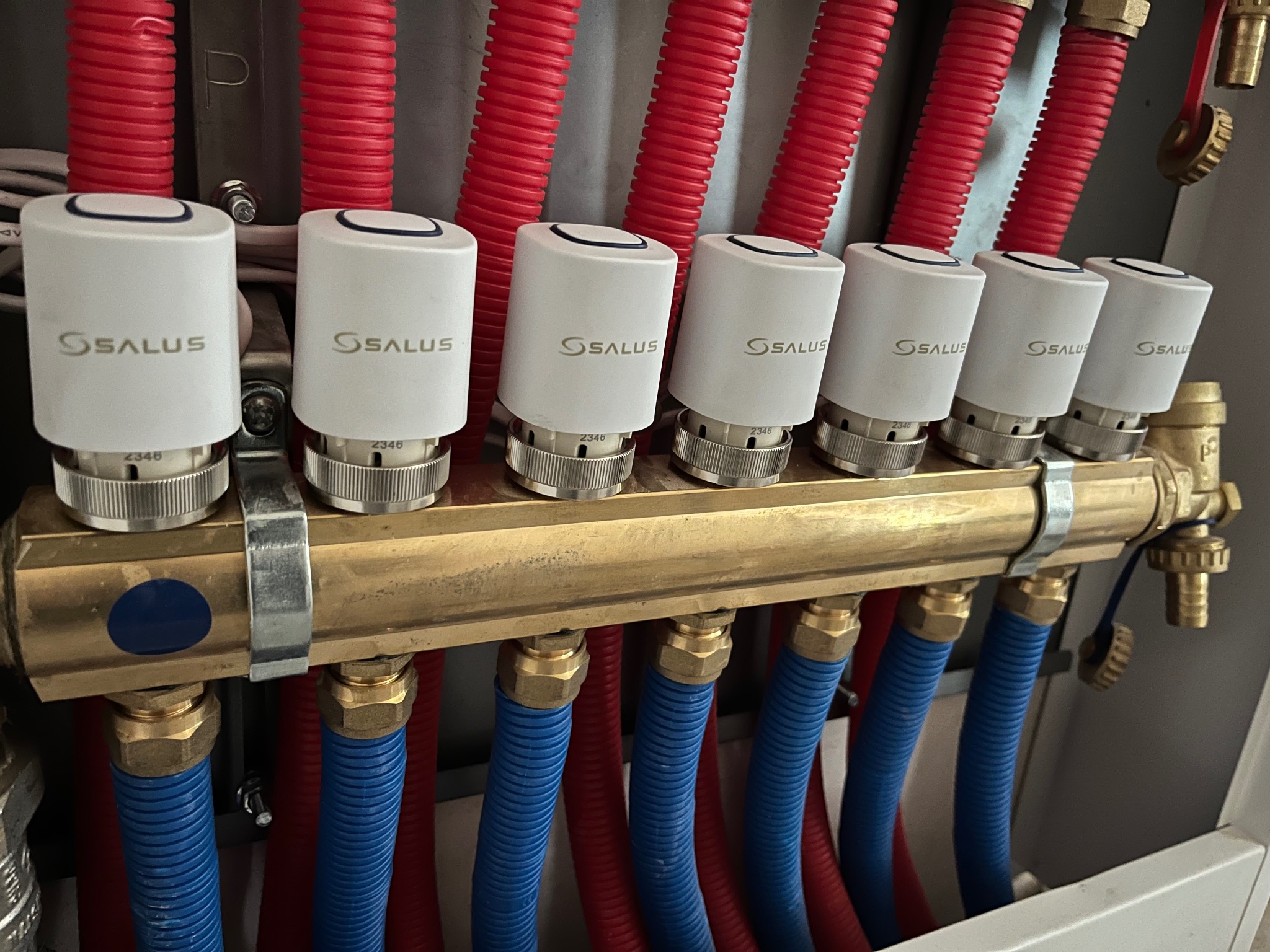 Rozdzielacz ogrzewania podłogowego z termostatami Salus, rury czerwone i niebieskie. Usługa instalacji w Częstochowie.