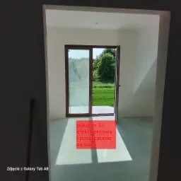 Wnętrze pokoju z widokiem na zewnątrz przez otwarte drzwi balkonowe, ściany przygotowane do malowania, podłoga z widocznymi śladami po pracach wykończeniowych, widoczne cienie.