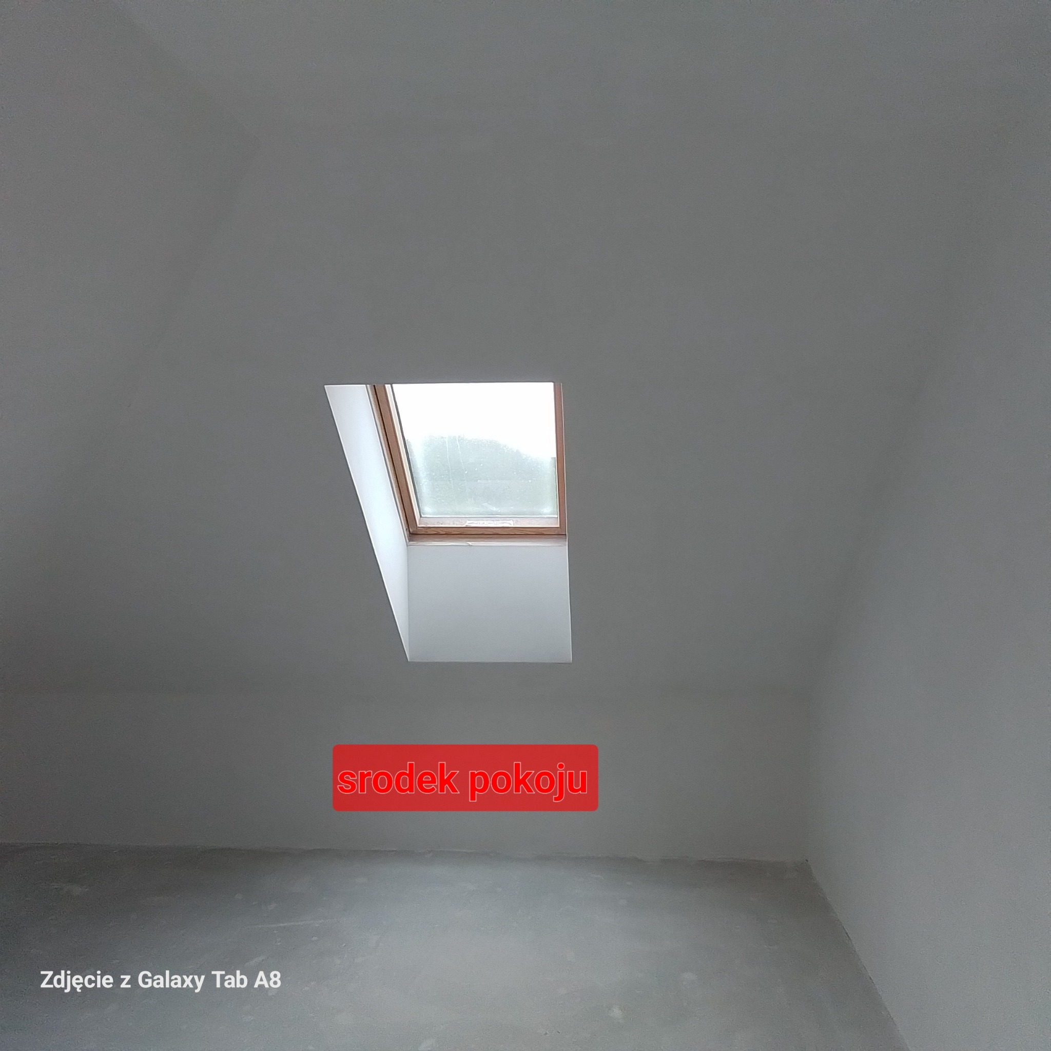 Surowe ściany i podłoga w pokoju na poddaszu z oknem dachowym, przygotowane do dalszych prac wykończeniowych.