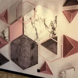 Dekoracyjna ściana z geometrycznymi panelami 3D w odcieniach różu, szarości i marmuru, tworząca nowoczesny wzór.