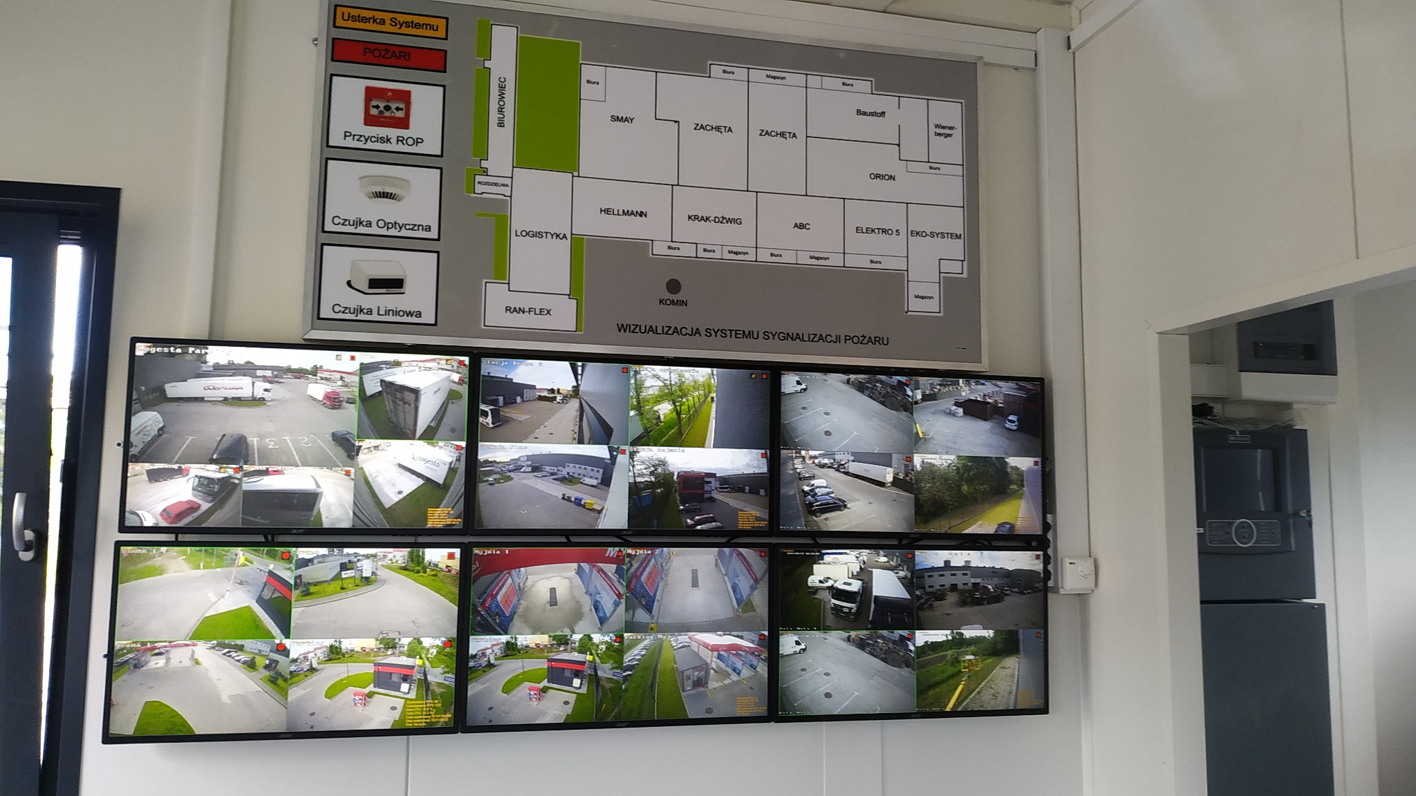 Centrum monitoringu wizyjnego z ekranami wyświetlającymi obraz z kamer przemysłowych na terenie zakładu, obok schemat systemu sygnalizacji pożaru.