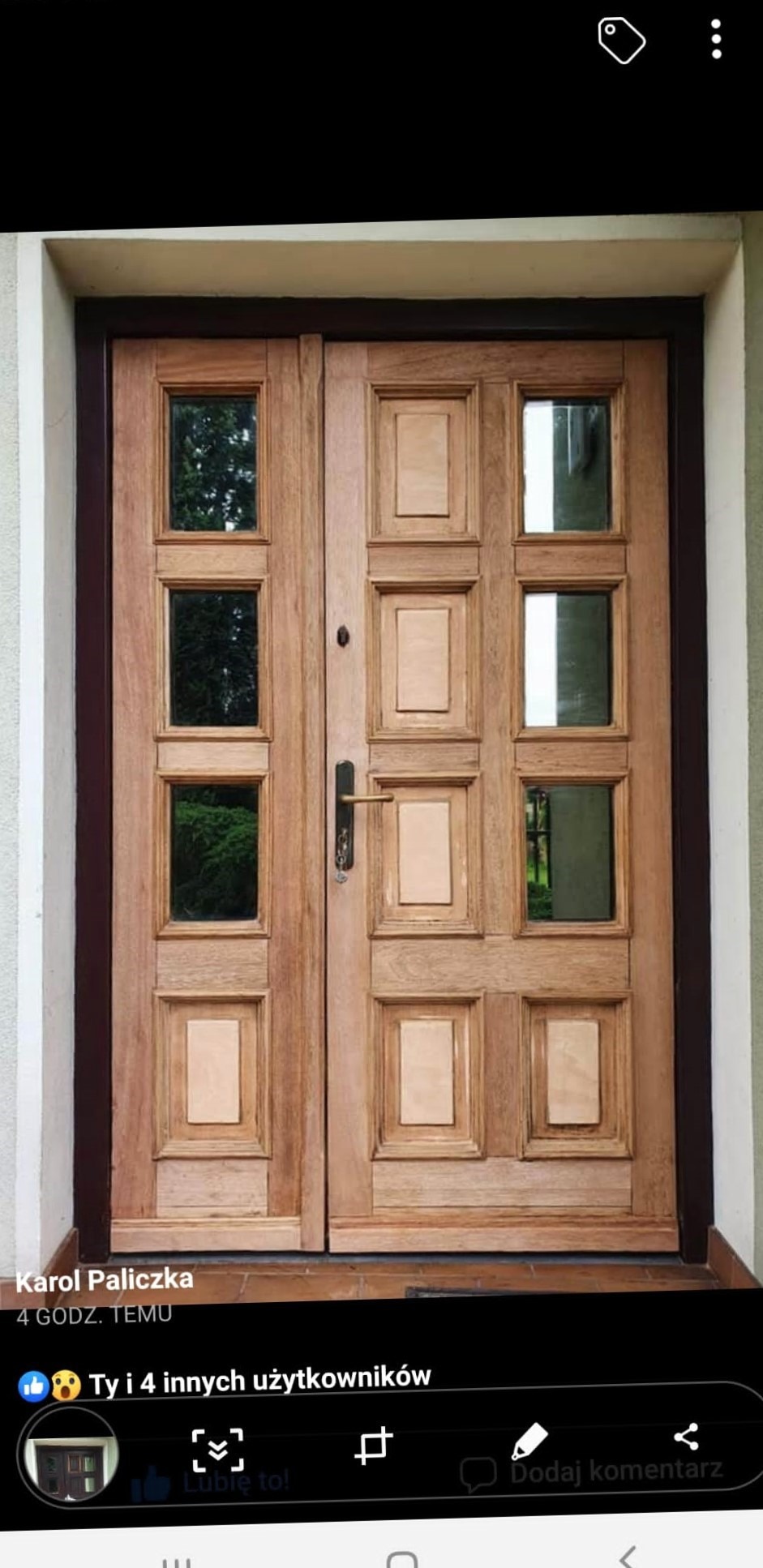 Dwuskrzydłowe drewniane drzwi wejściowe z przeszkleniami w kwadratowych ramkach, widok z zewnątrz, surowe drewno przed wykończeniem.