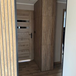 VIT - DOM VITALII PETRYSHYN - Wykończenie wnętrza: drewniana okleina ścienna z pionowymi listwami obok drzwi z poziomymi panelami. Podłoga z paneli imitujących drewno.