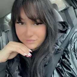 Portret kobiety z ciemnymi włosami i manicure w samochodzie, zapięta pasami bezpieczeństwa