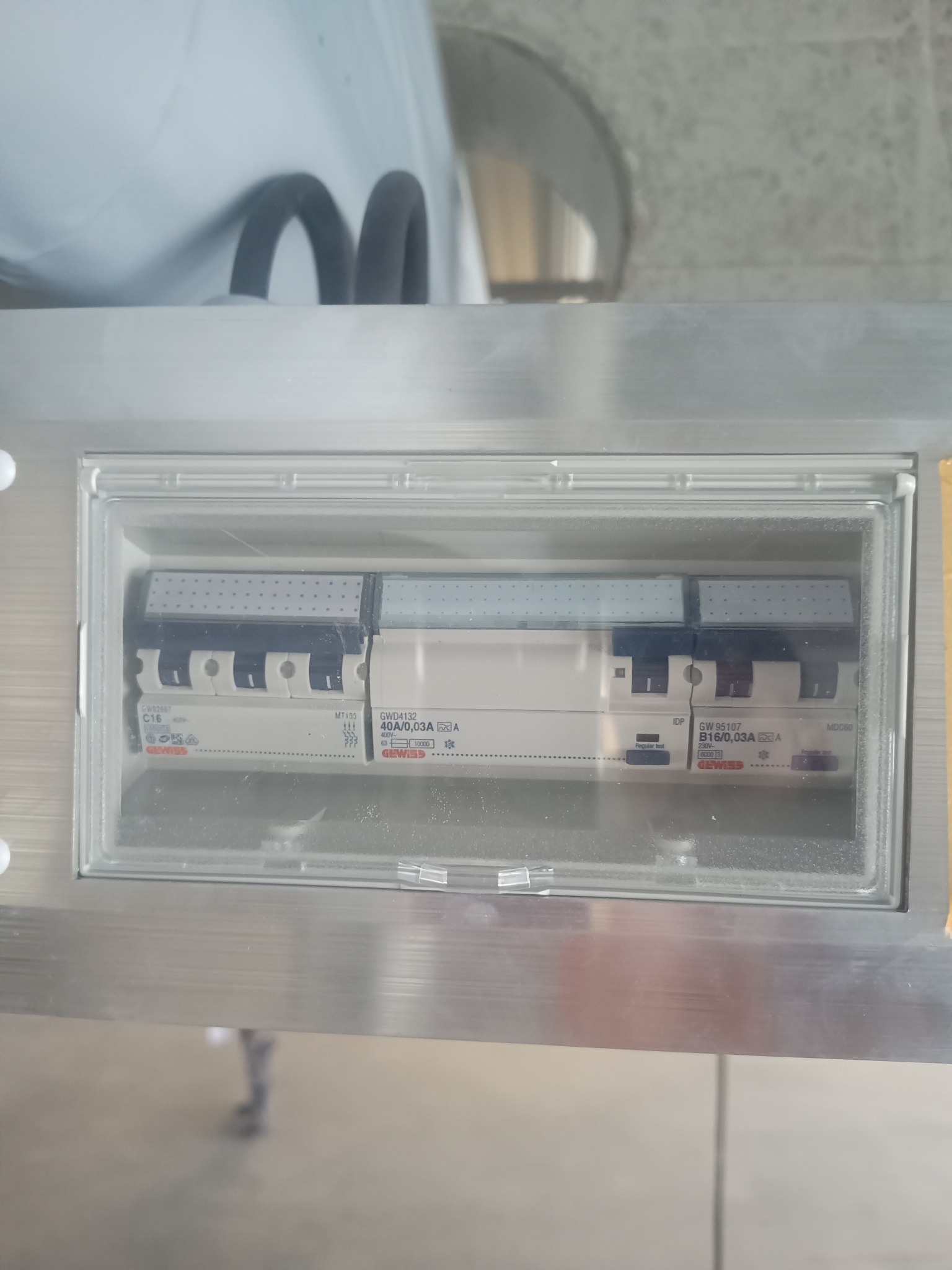 Rozdzielnica elektryczna z trzema bezpiecznikami różnicowoprądowymi Gewiss w obudowie z przezroczystą pokrywą, widoczne oznaczenia C16, B16 i 40A/0,03A.