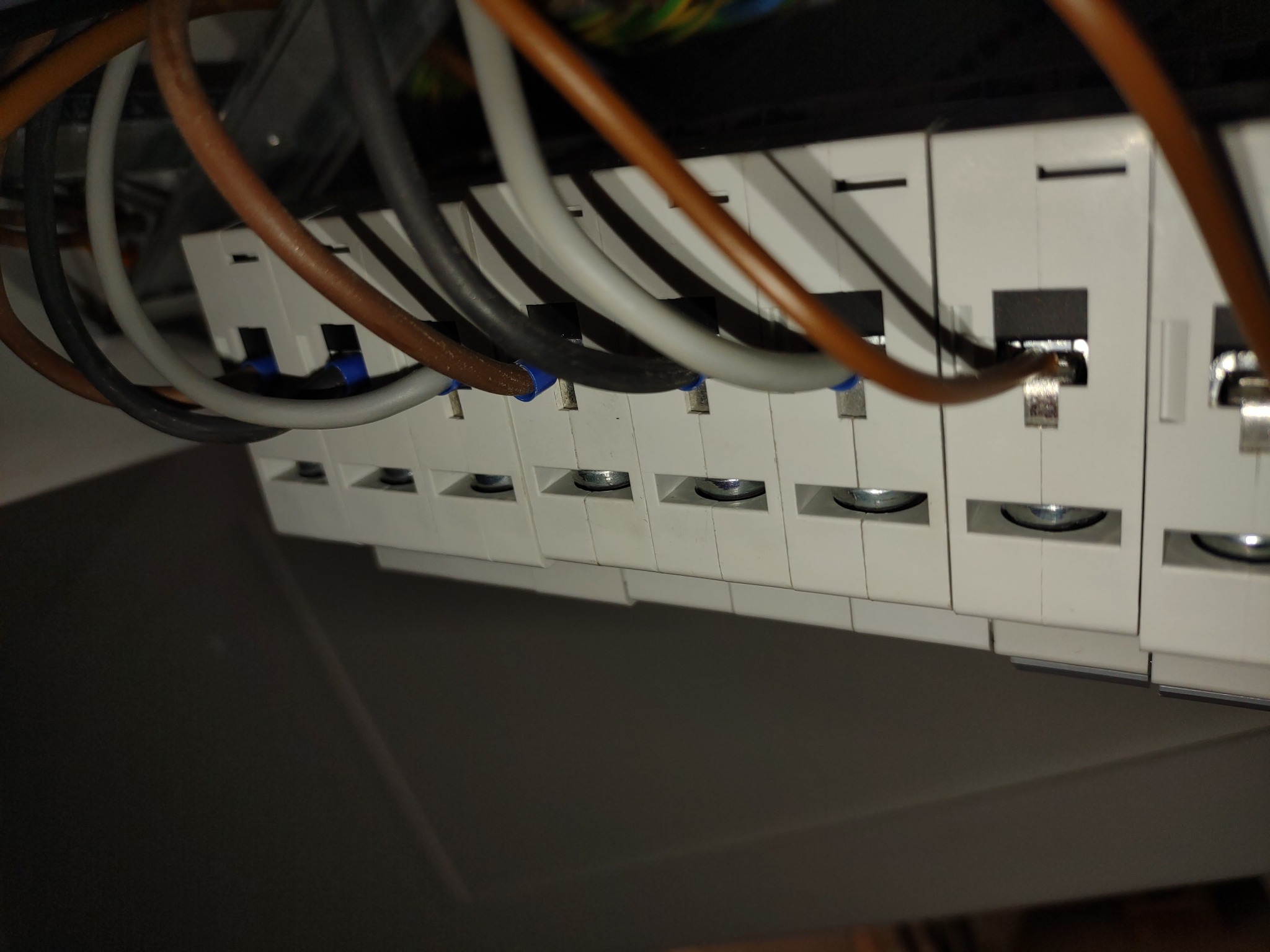 Szereg złączek elektrycznych z podłączonymi przewodami w różnych kolorach, widoczne śruby mocujące, instalacja w rozdzielnicy.