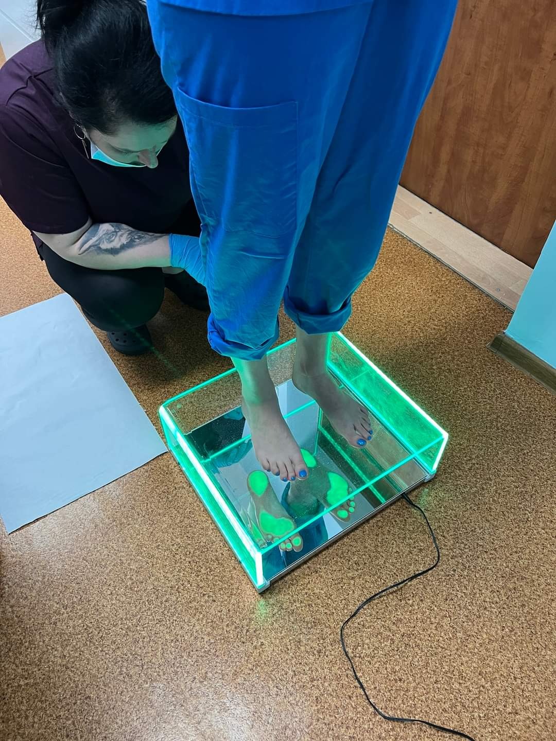 Pacjentka w Zawierciu podczas badania stóp na podoskopie z podświetleniem LED, wykonywanym przez specjalistę w rękawiczkach.