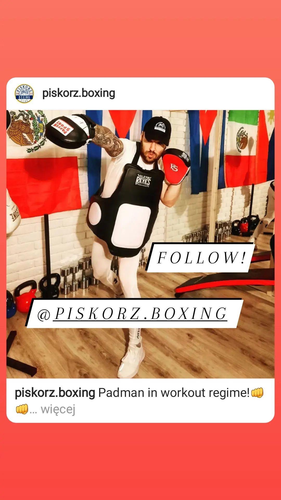 Mężczyzna w czapce i ochraniaczu na korpusie, trzymający tarcze bokserskie w rękach, w tle flagi Meksyku i Polski, oraz sprzęt do ćwiczeń.