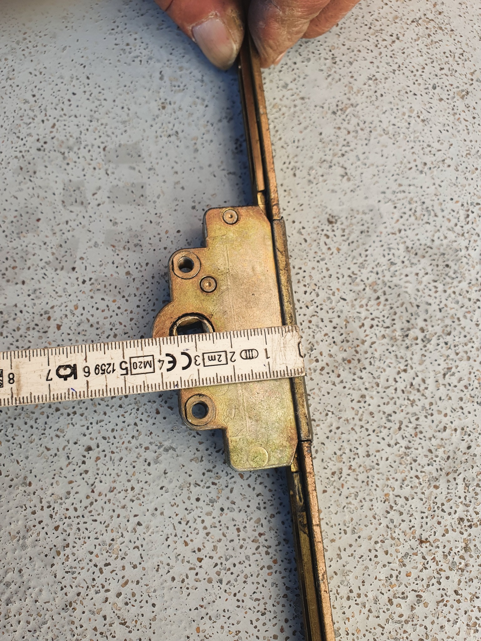 Pomiar suwakiem zamka okiennego na szarym, nakrapianym tle.