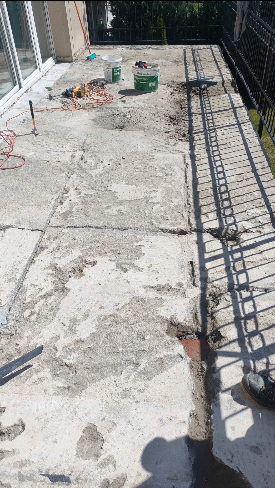 Przygotowanie tarasu do remontu w Zielonej Górze: widoczne narzędzia, wiaderka z masą szpachlową i częściowo usunięta stara nawierzchnia.