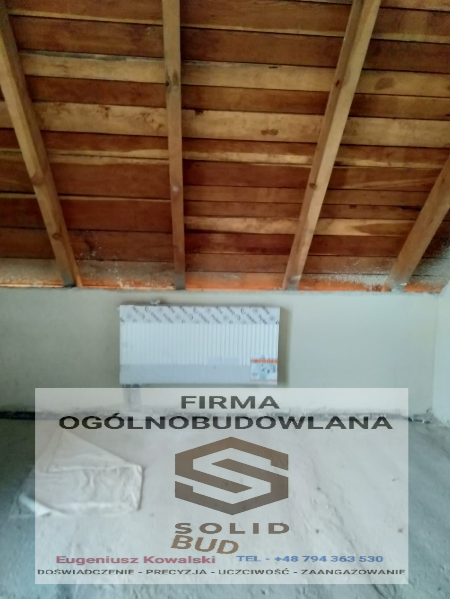 Płyta styropianowa zamontowana na ścianie pod drewnianą konstrukcją dachu poddasza, widoczna folia ochronna na płycie.