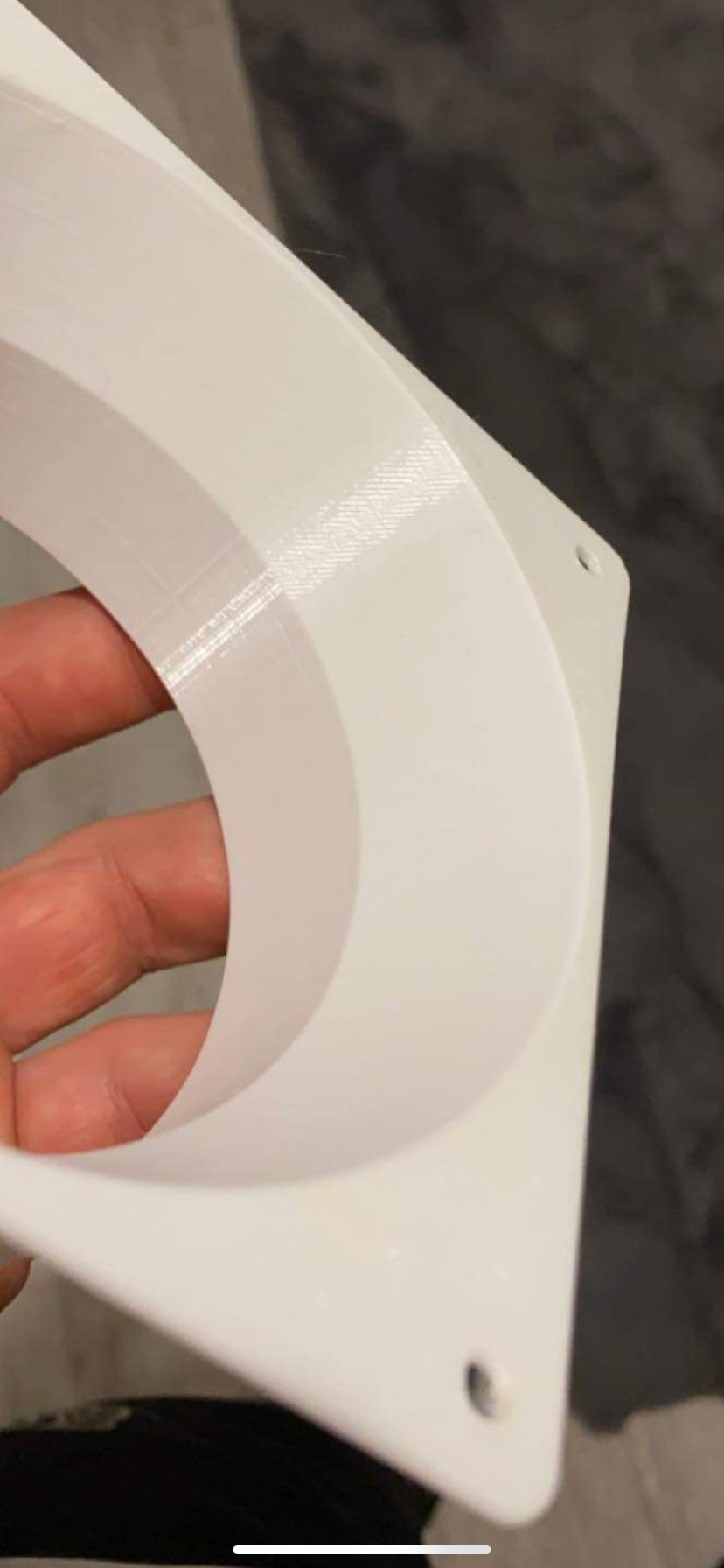 Biały adapter redukcyjny, wydrukowany w technologii FDM, trzymany w dłoni, widoczne warstwy druku i otwory montażowe.