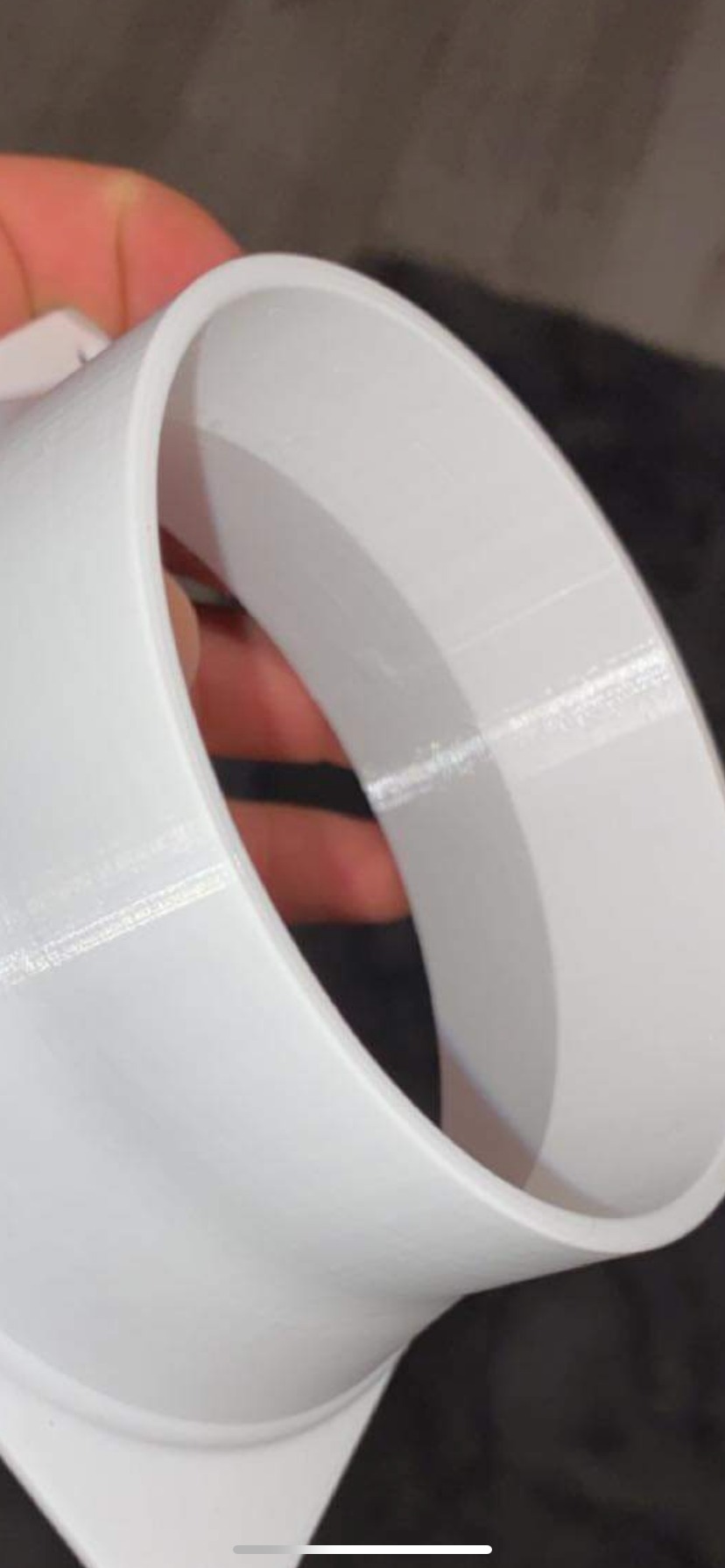 Biały, wydrukowany w 3D element rurowy, trzymany w dłoni, widoczne warstwy druku.