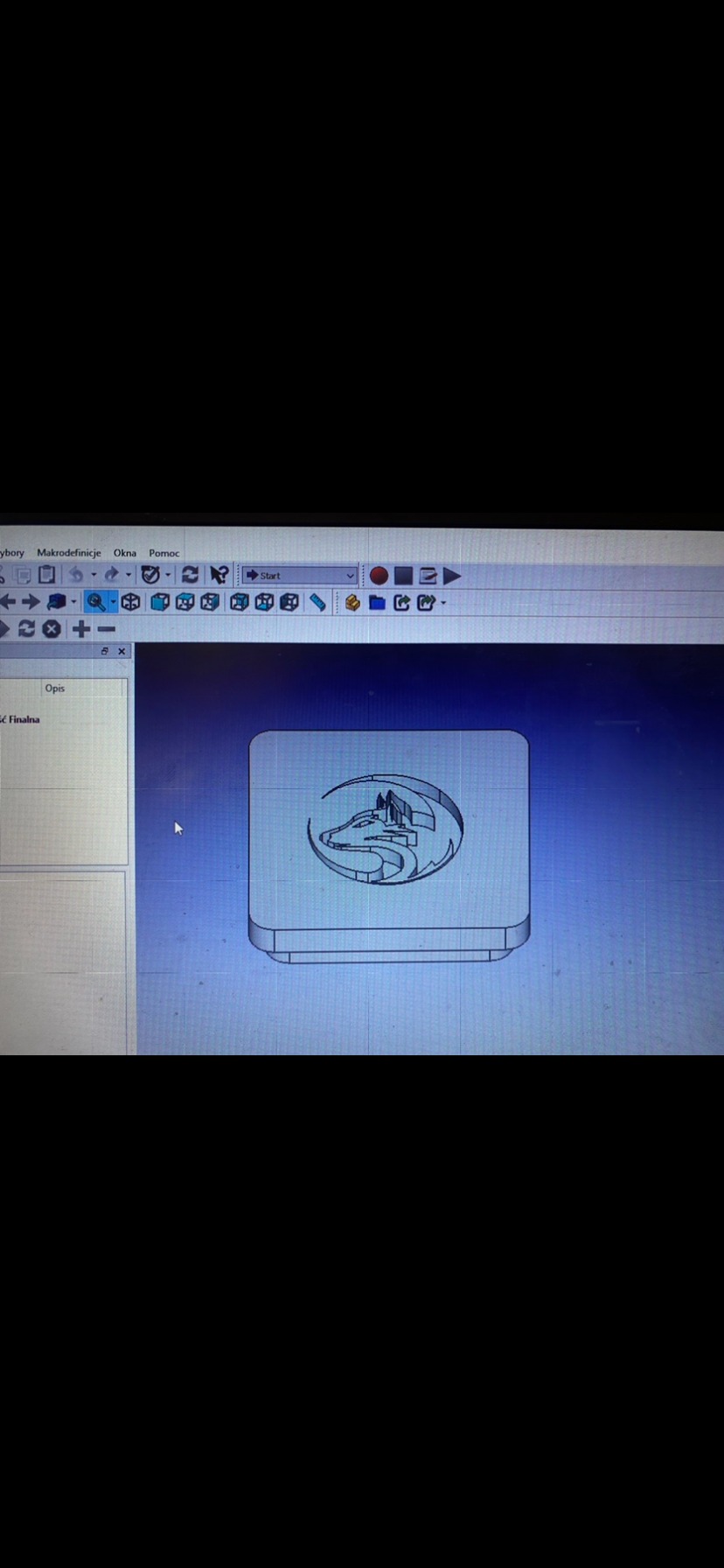 Ekran monitora z otwartym programem do projektowania. Widoczny model 3D w kształcie zaokrąglonego kwadratu z wygrawerowanym motywem wilka w kole.