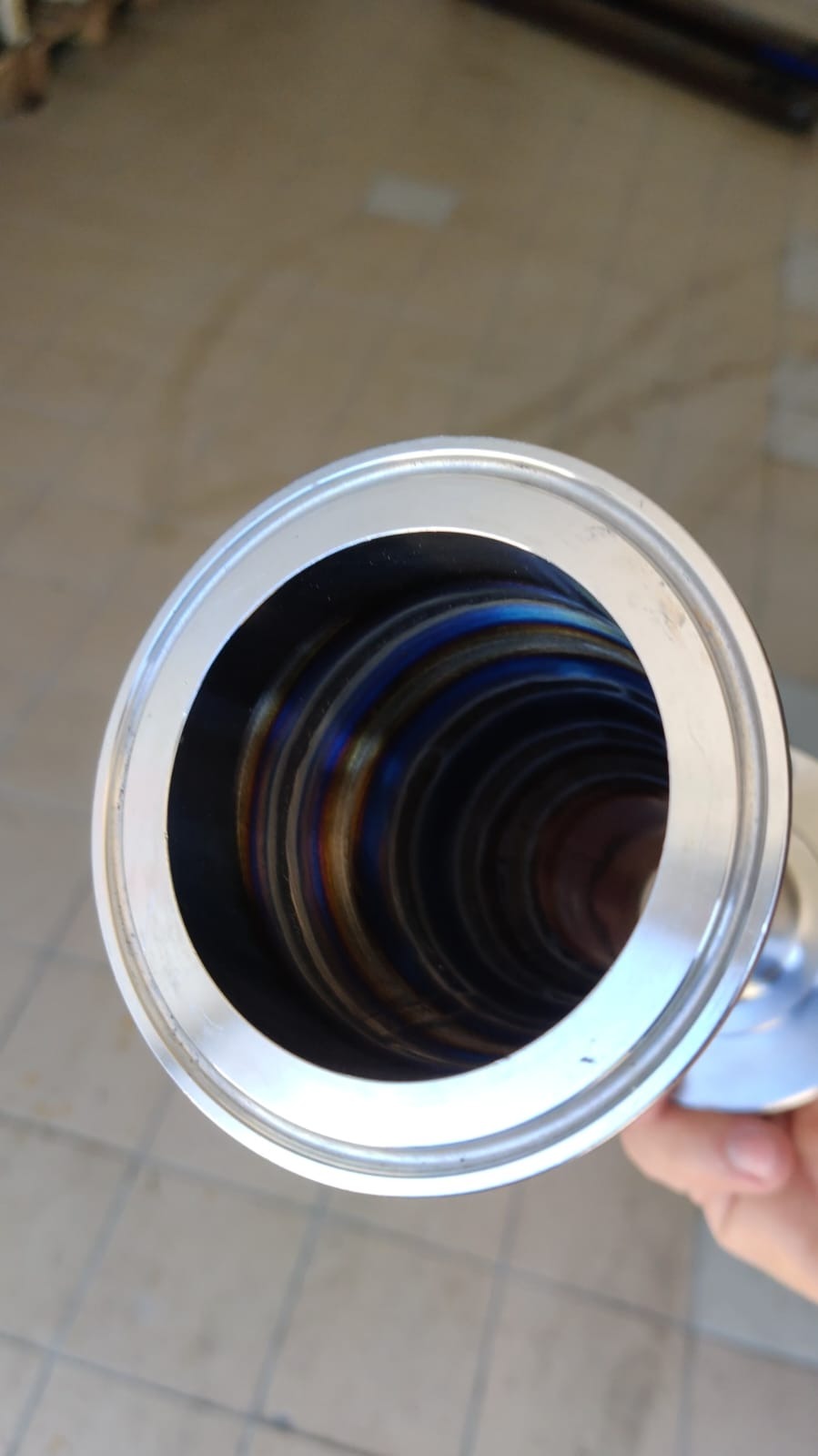 Wnętrze rury ze stali nierdzewnej z widocznymi wielobarwnymi śladami spawania TIG, uchwycone z bliska pod kątem.