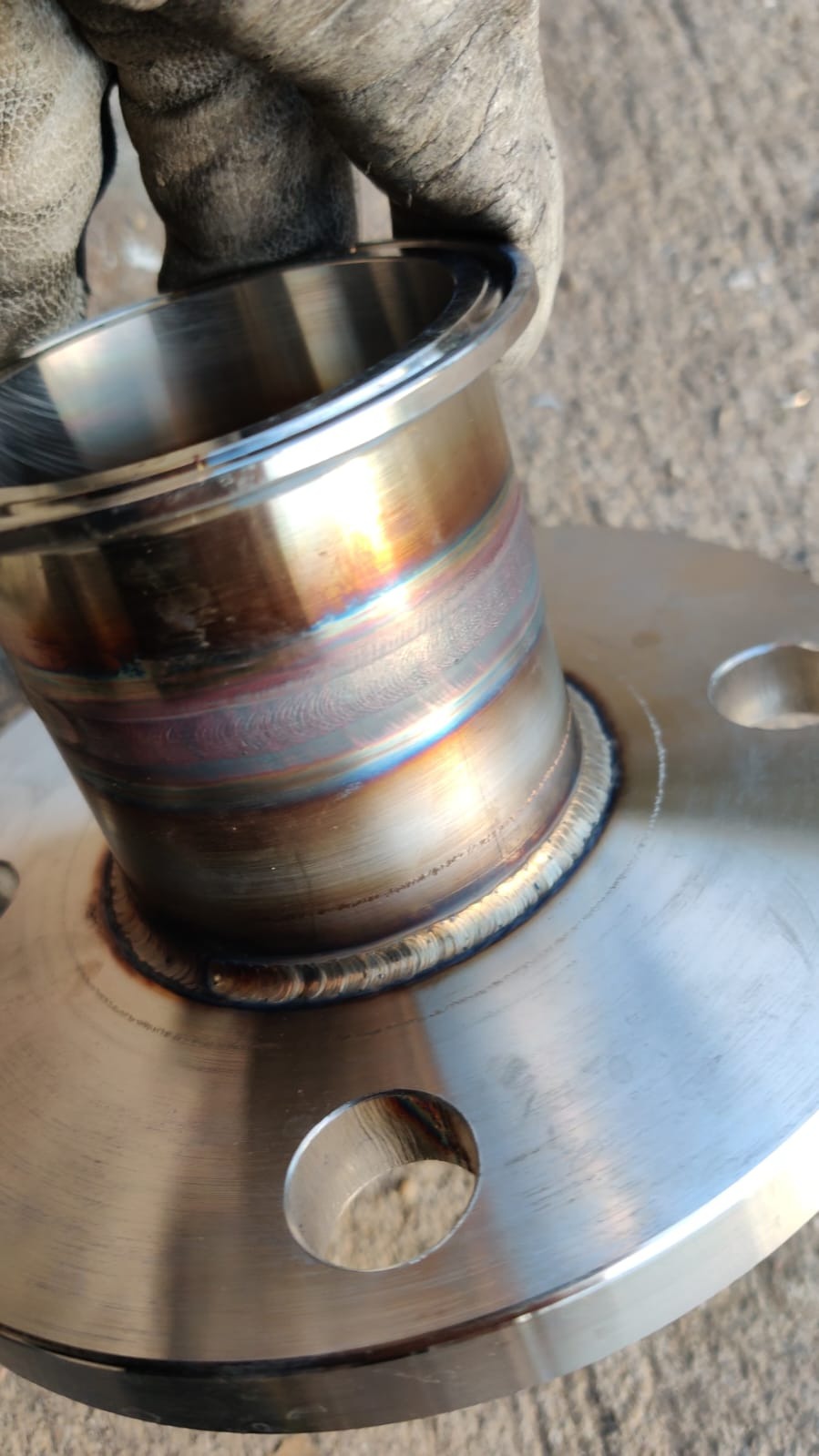 Spoina obwodowa rury ze stali nierdzewnej do kołnierza, widoczne przebarwienia termiczne i ślady szlifowania, trzymana w rękawicy roboczej.