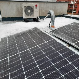 Opal-House - Instalacja paneli słonecznych i jednostki zewnętrznej klimatyzacji LG Therma V na płaskim, ośnieżonym dachu budynku.