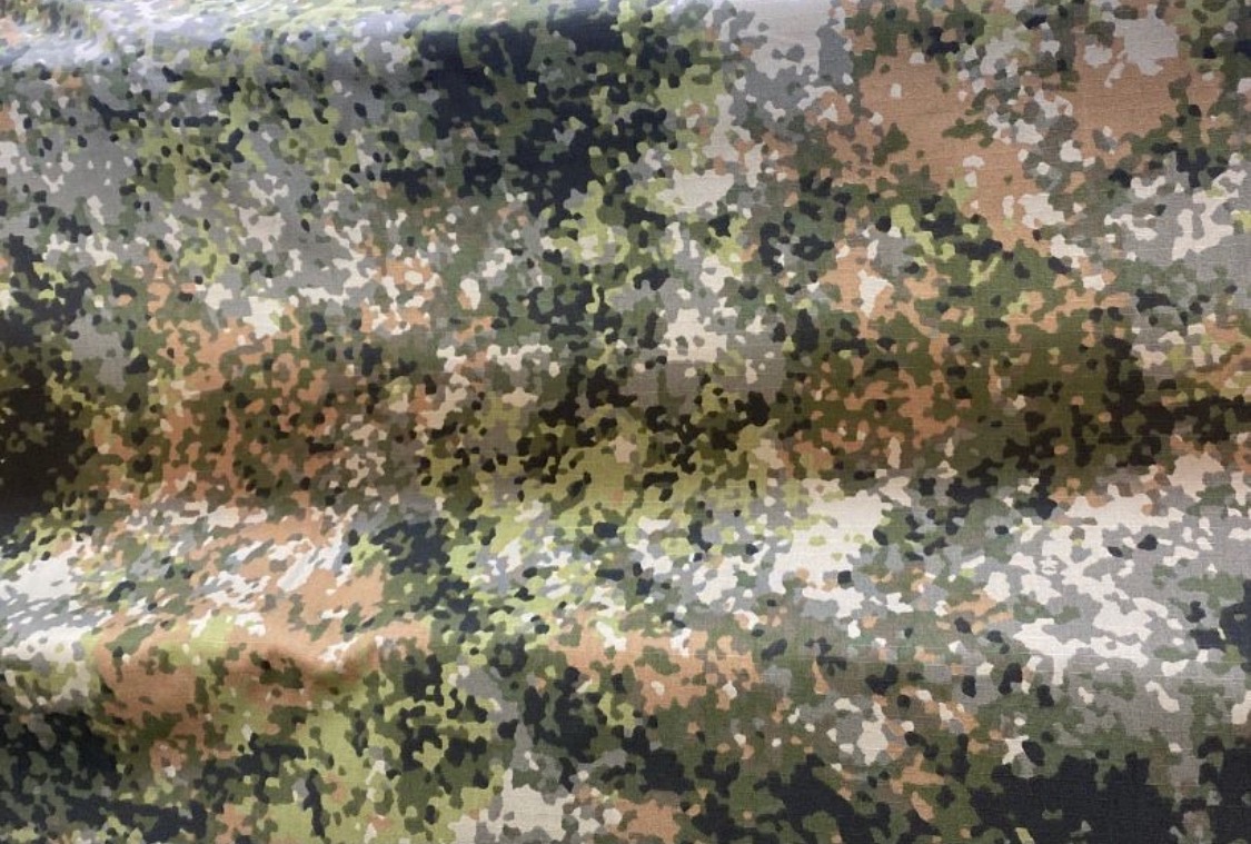 Fragment tkaniny w kamuflażu pikselowym, z widocznymi fałdami i detalami splotu.