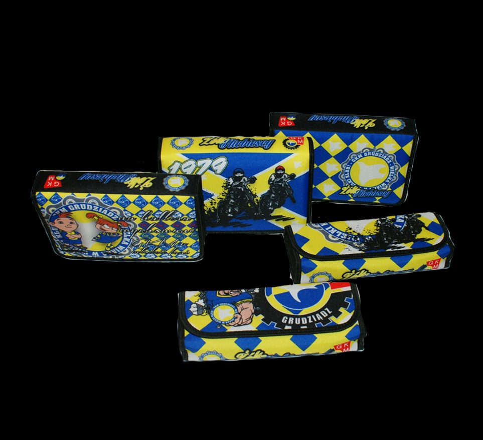 Kolekcja kosmetyczek z nadrukami w barwach klubu żużlowego GKM Grudziądz, ukazująca różne wzory i motywy, w tym grafiki zawodników i logo klubu na czarnym tle.