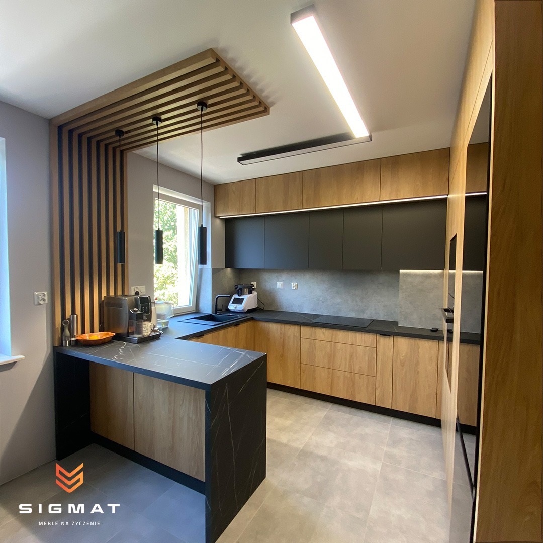 Nowoczesna kuchnia z drewnianymi szafkami dolnymi, czarnymi szafkami górnymi i blatem z czarnego marmuru, oświetlona lampami LED i dekoracyjną drewnianą kratownicą sufitową.