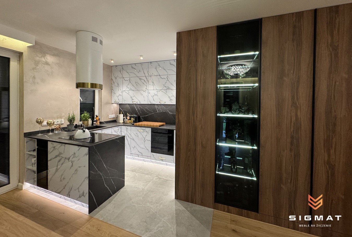 Nowoczesna kuchnia na wymiar we Wrocławiu z wyspą i marmurowymi frontami, oświetleniem LED pod szafkami i wysoką zabudową z przeszkloną witryną na dekoracje.
