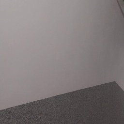 Dag-Bud S.C. - Klatka schodowa po odświeżeniu: pomalowana na szaro ściana kontrastuje z dolną częścią ściany wykończoną szorstkim, ciemnoszarym tynkiem strukturalnym. Widoczne fragmenty schodów z dekoracyjnymi...