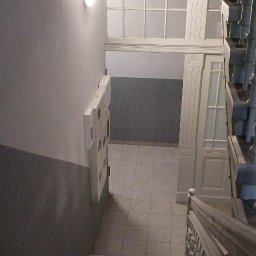 Dag-Bud S.C. - Klatka schodowa w kamienicy po odświeżeniu, widok z góry na schody z metalowymi listwami antypoślizgowymi, pomalowane ściany i odnowiona stolarka okienna oraz drzwiowa.