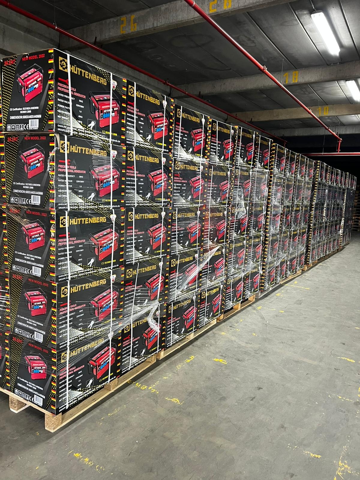 Magazyn składowanych palet z zapakowanymi agregatami prądotwórczymi marki Huttenberg, owinięte folią stretch.