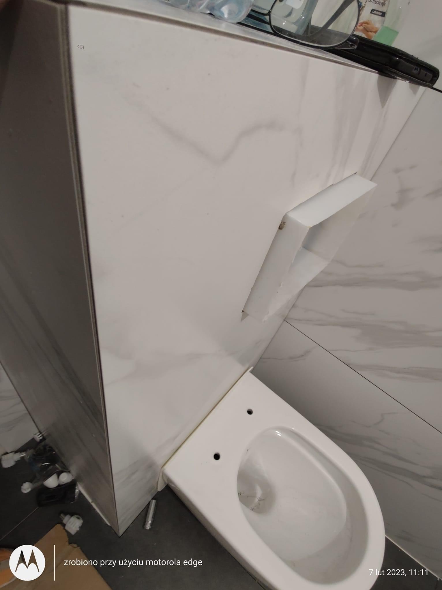 Zamontowana miska WC podwieszana na stelażu w łazience wykończonej płytkami imitującymi marmur, widoczne elementy instalacji na podłodze.