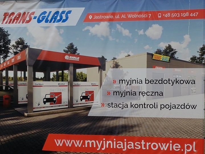 Reklama myjni samochodowej Trans-Glass w Jastrowiu, oferującej myjnię bezdotykową, ręczną oraz stację kontroli pojazdów, widoczna nazwa EHRLE.