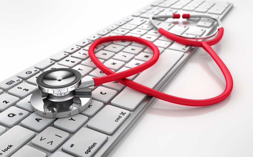 Stetoskop lekarski koloru czerwonego leży na białej klawiaturze komputera, symbolizując diagnozę lub naprawę problemów z komputerem.