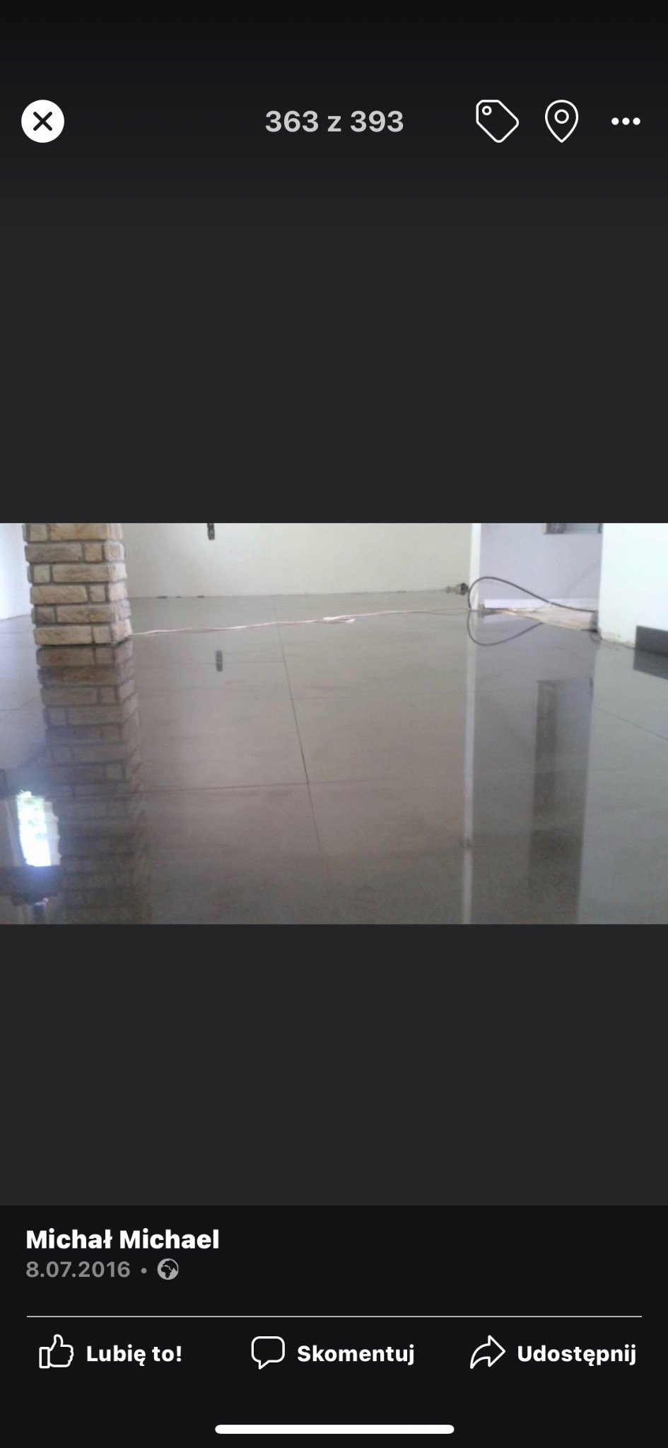 Wypoziomowana, błyszcząca posadzka w jasnym pomieszczeniu z kolumną wykończoną cegłą klinkierową, widoczne odbicia światła i elementów wyposażenia.