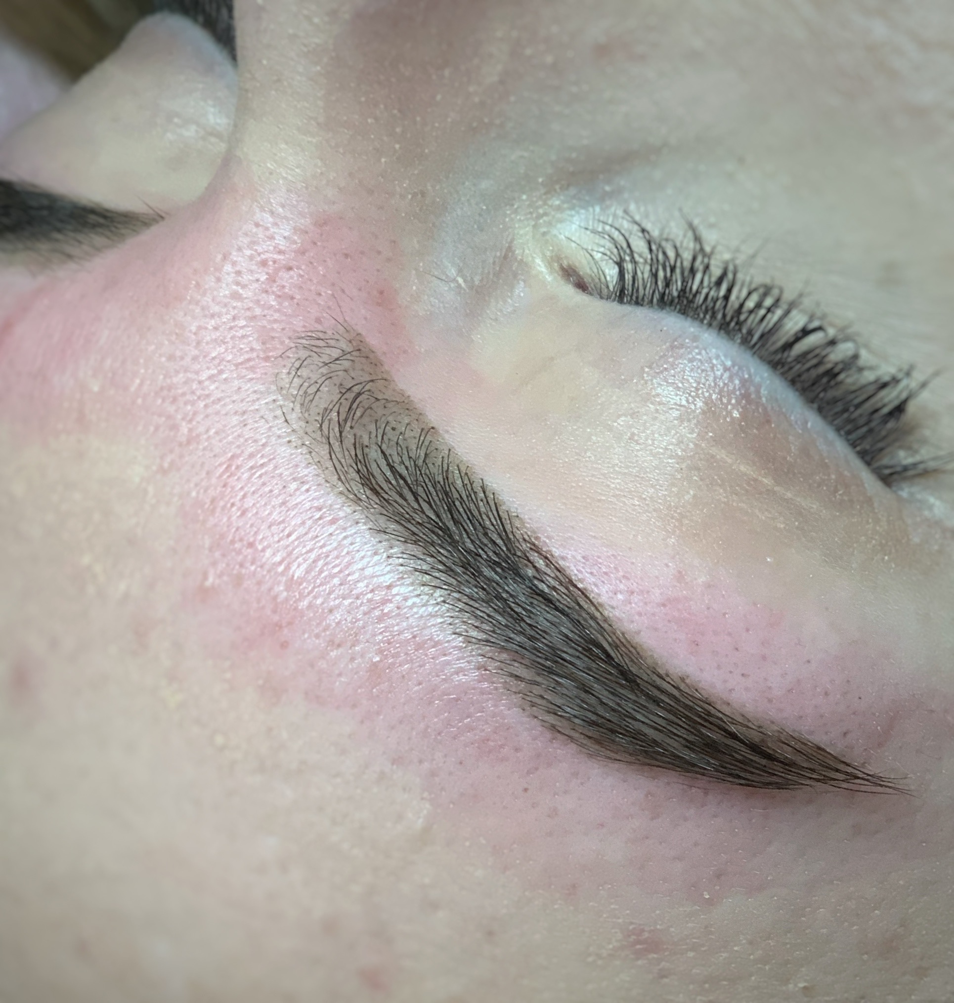 Zamknięte oko z widoczną brwią po zabiegu microbladingu, skóra lekko zaczerwieniona.