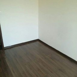 Flex Bud - Wnętrze pokoju po remoncie: ściany pomalowane na jasny odcień, ciemna, lakierowana podłoga z paneli oraz listwy przypodłogowe.