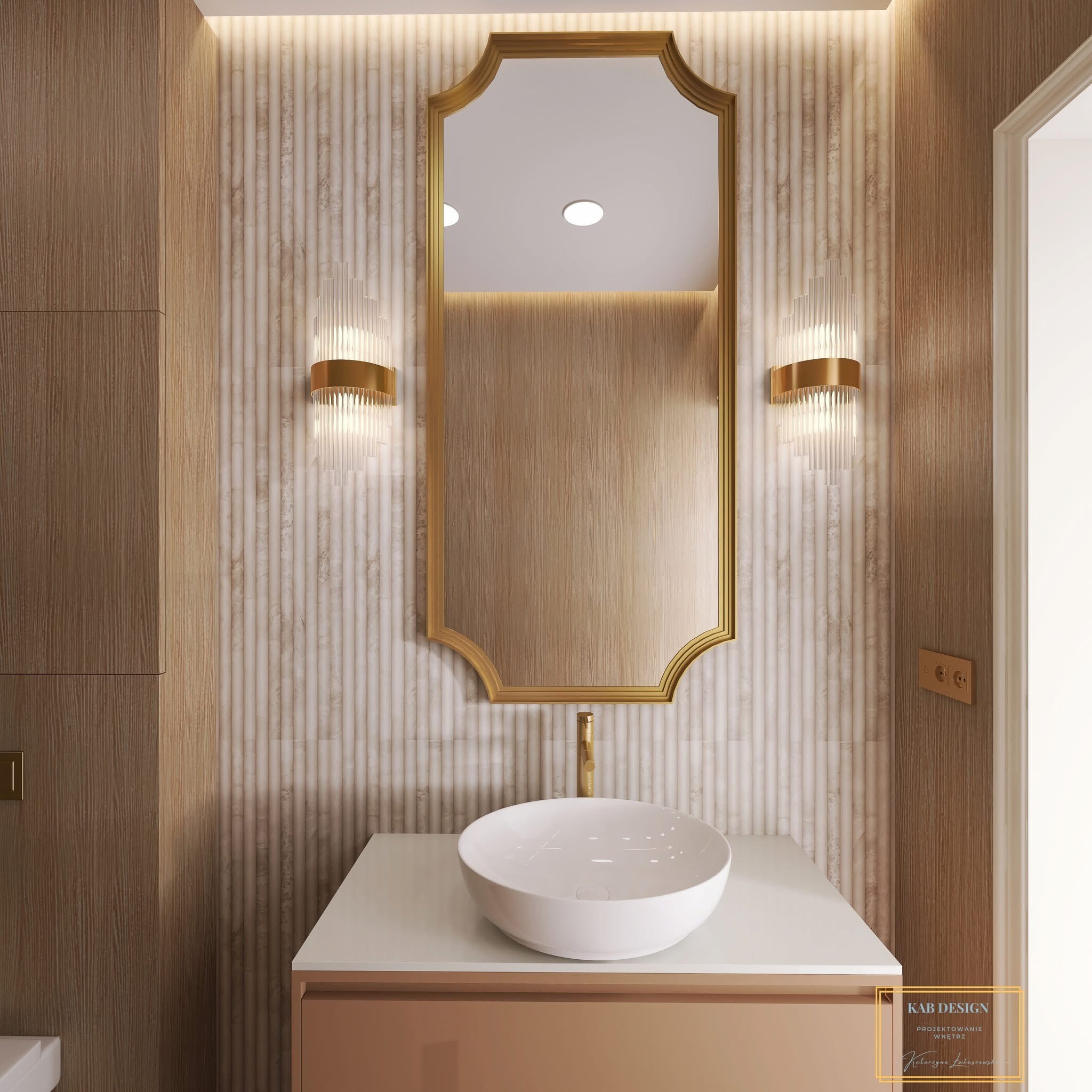 Elegancka łazienka z umywalką nablatową, złotą armaturą i lustrem w ozdobnej ramie. Ściany wykończone w beżowych odcieniach, oświetlenie punktowe.