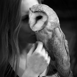 Monika Łopatka - Portret kobiety z sową płomykówką trzymaną na rękawicy, czarno-białe zdjęcie z widocznym zegarkiem na nadgarstku.