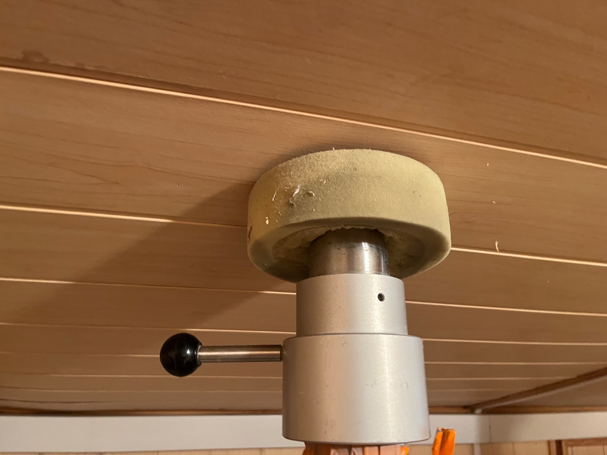 Aplikator pianki montażowej dociskany do drewnianego sufitu podczas ocieplania poddasza, widoczne drobne resztki pianki na aplikatorze.