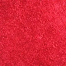 Czerwona, teksturowana powierzchnia o krótkim włosiu, przypominająca dywan lub wykładzinę.