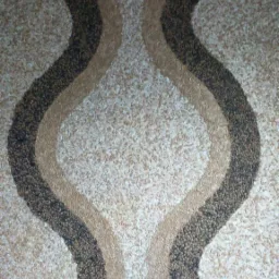 Ściana pokryta dekoracyjną strukturą z wzorem fal w odcieniach beżu i brązu, imitująca naturalny kamień.